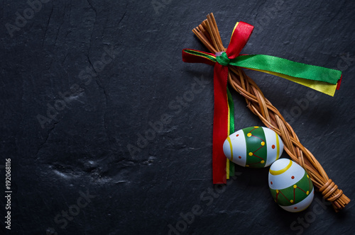 Colorized Easter eggs and whip on stone table. Symbol of a Christian religion vacation. Spring folk tradition background.