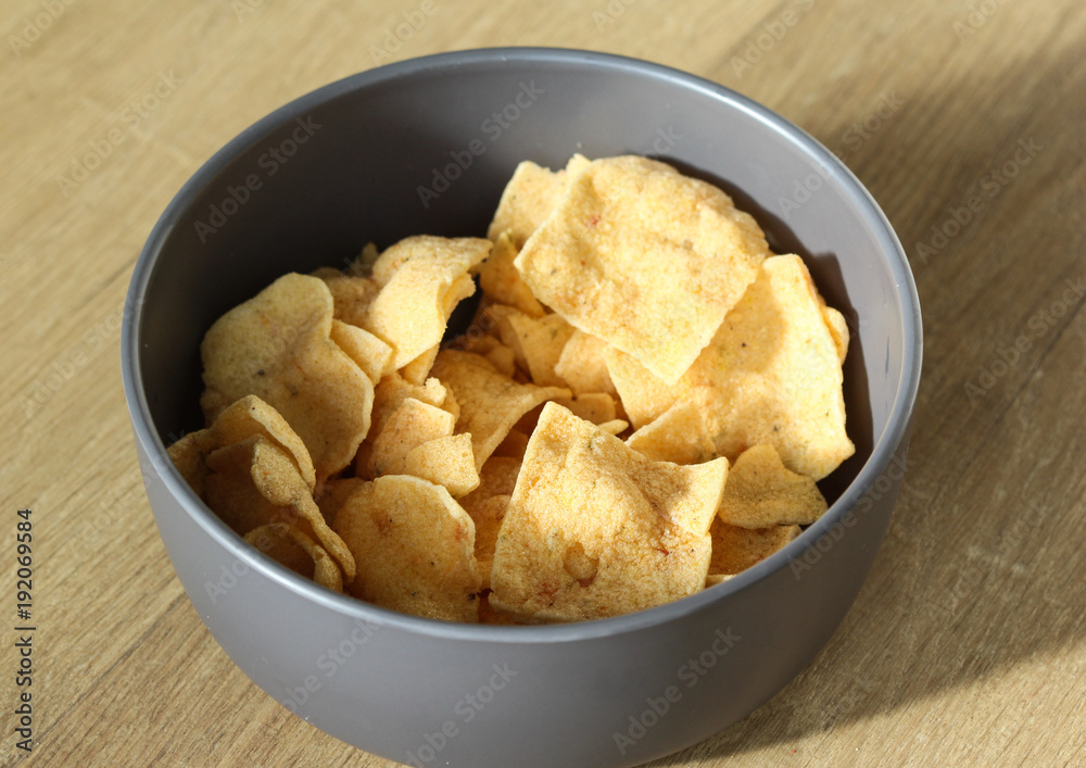 Bowl with Indonesian cassave chips on wooden background Bowl with Indonesian cassave chips on wooden background