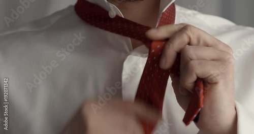 Businessman putting on red tie. Getting ready for work.