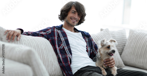 stylish guy sitting on the couch with his dog.