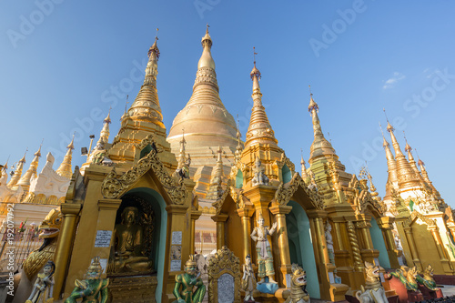 Small pagodas and statues in front of the gilded Shwedagon Pagoda in Yangon  Myanmar on a sunny day.