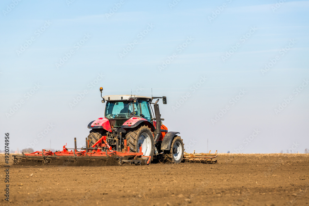Obraz premium Farmer in tractor preparing land with seedbed cultivator as part of pre seeding activities in early spring season of agricultural works at farmlands.