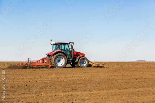 Farmer in tractor preparing land with seedbed cultivator as part of pre seeding activities in early spring season of agricultural works at farmlands.