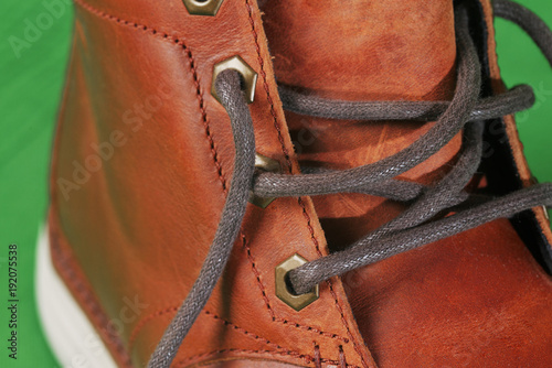 winter brown leather boots on a green background. Modern fashion and style. bootlace Closeup.