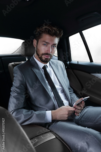 man in suit sitting in car and reading messages on smartphone © ASDF