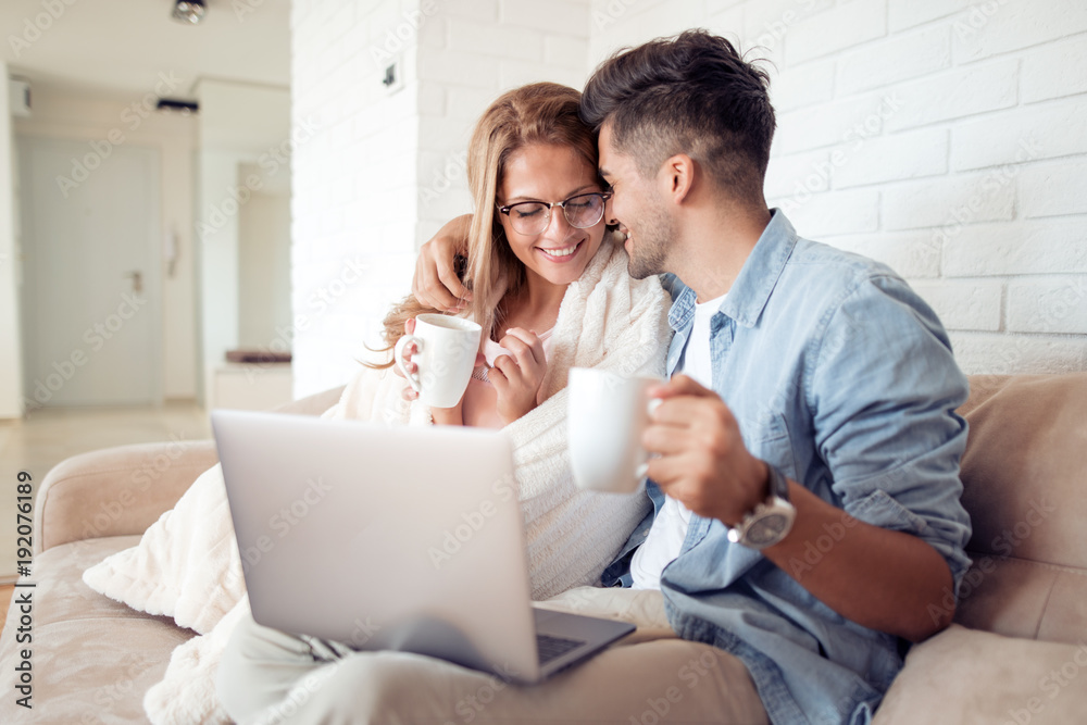 Obraz premium Couple with a laptop sitting under the blanket.