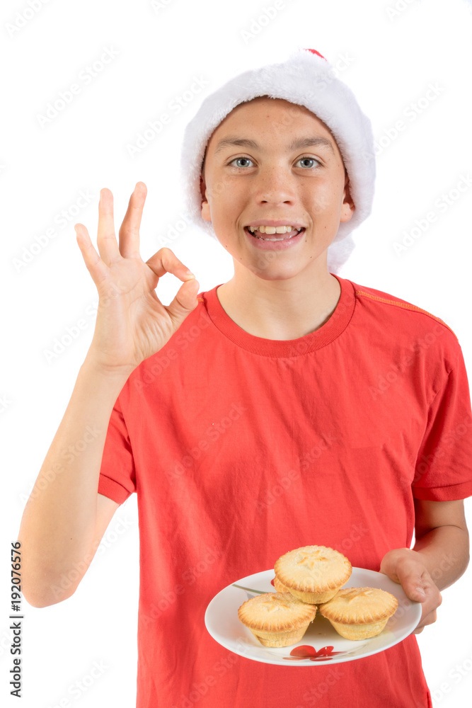 Teenage boy isolated on white background with a plate of mince pies Teenage boy isolated on white background with a plate of mince pies