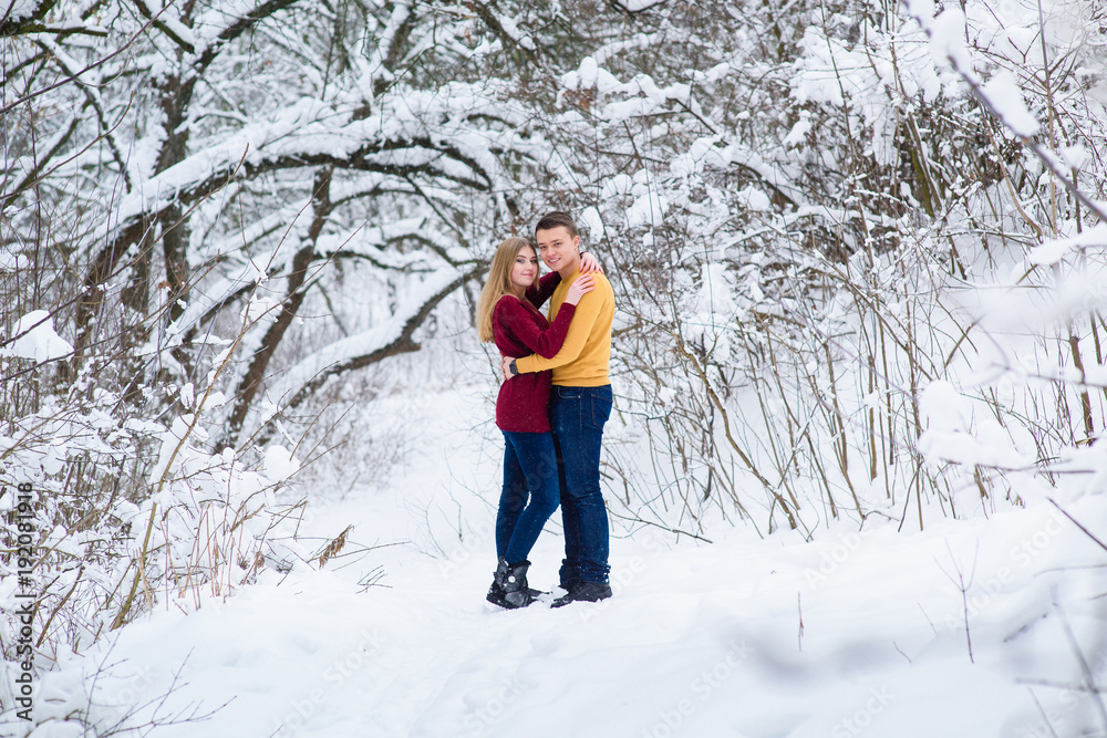 Young couple hug in winter forest