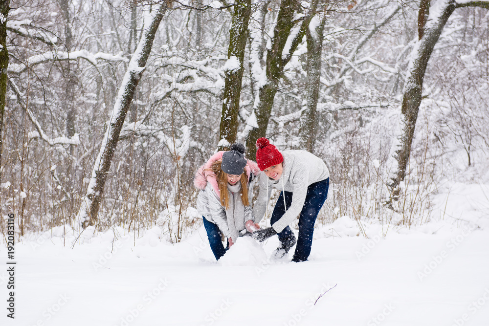 Young couple making snowman in forest