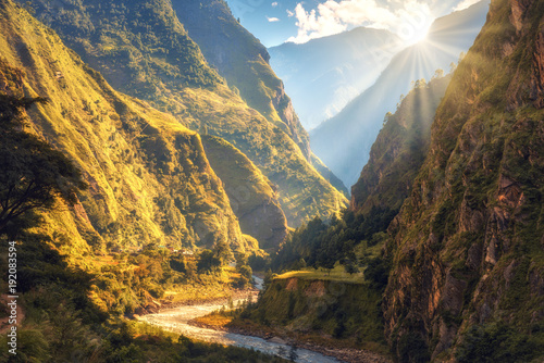Fototapeta Naklejka Na Ścianę i Meble -  Colorful landscape with high Himalayan mountains, beautiful curving river, green forest, blue sky with clouds and yellow sunlight at sunset in autumn in Nepal. Mountain valley. Travel in Himalayas