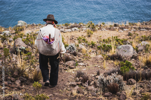 Poor man walking down a cliff, Taquile Island, Titicaca lake, Peru photo
