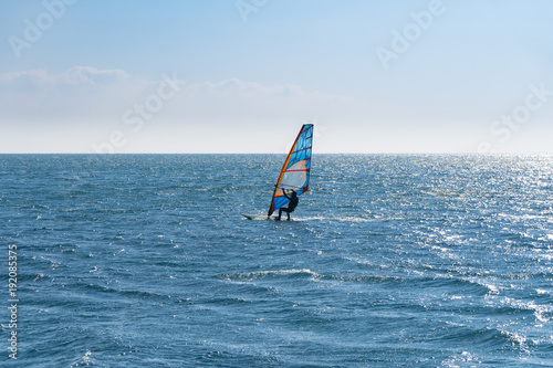 Windsurfing on the sea, backlit view.