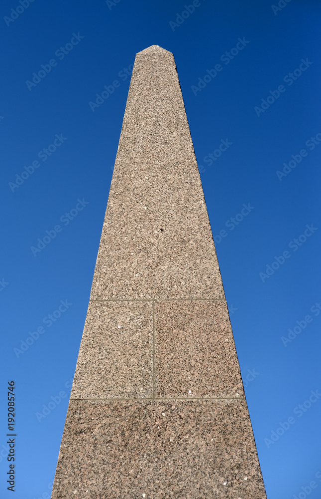 Granite stele on blue sky background.
