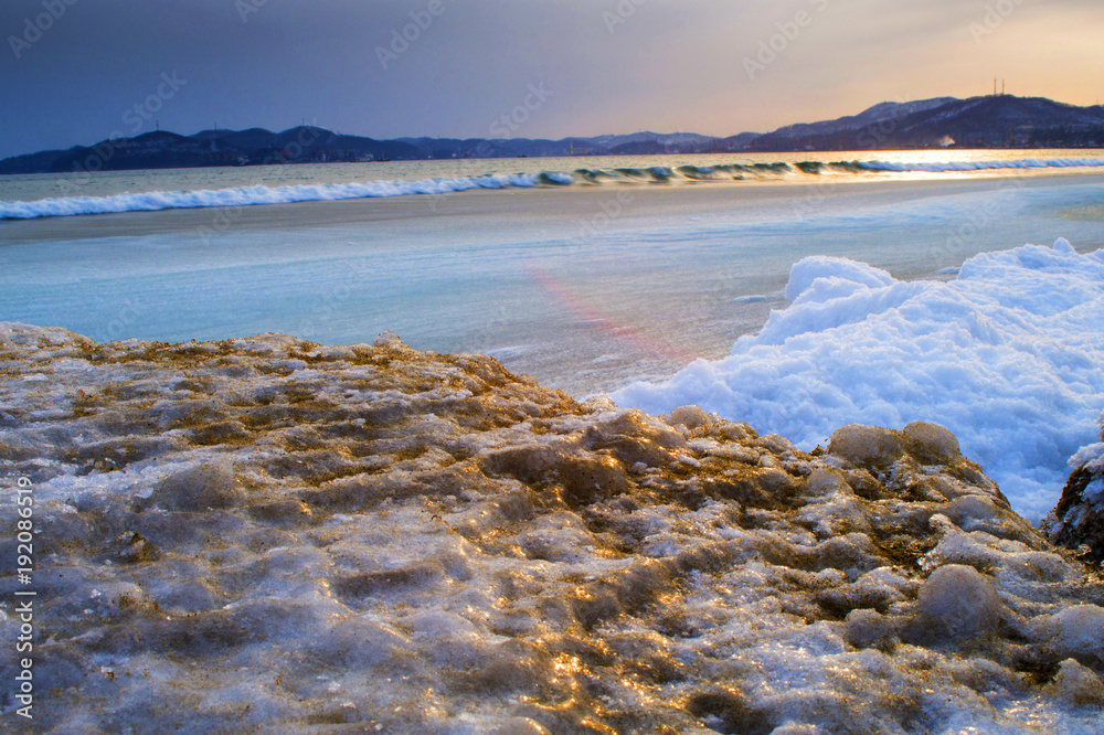sunset on the winter sea, golden waves, evening at the winter beach