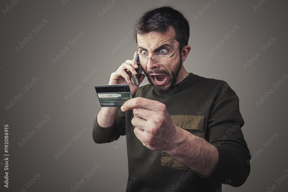 Angry young man having an argument with his bank for the credit card bill he received Angry young man having an argument with his bank for the credit card bill he received