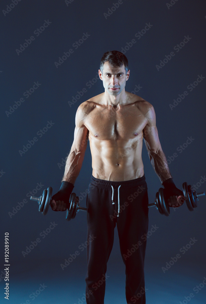 Handsome muscular man working out with dumbbells. Personal fitness instructor. Personal training.
