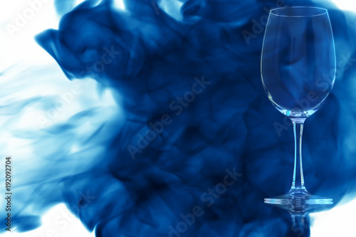 An empty glass of red wine or water enveloped in blue smoke.