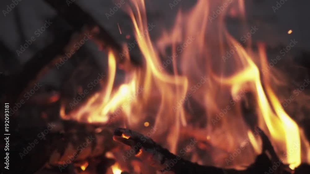 Firewood shaking burning orange flame in pile of bonfire lots of ashes and sparks in forest on winter night, slow motion close up shot Firewood shaking burning orange flame in pile of bonfire lots of ashes and sparks in forest on winter night, slow motion close up shot