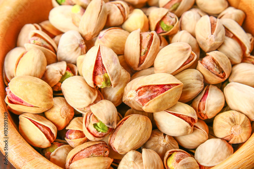 Dish full of pistachios with more pistachios on side. photo