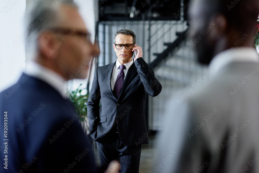 selective focus of businessman talking on smartphone in office selective focus of businessman talking on smartphone in office