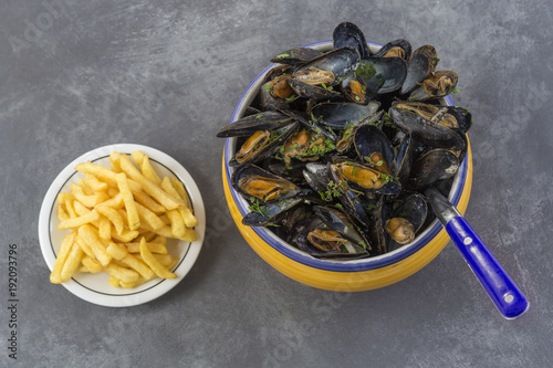 Foto French blue mussel with herbs in a yellow bowl with french fries glass ramekin o