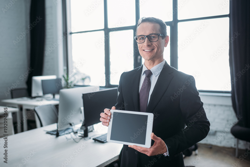 portrait of smiling businessman showing tablet with blank screen in hands in office portrait of smiling businessman showing tablet with blank screen in hands in office