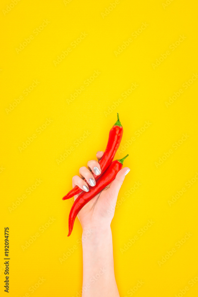 cropped shot of person holding raw red chilli peppers in hand isolated on yellow cropped shot of person holding raw red chilli peppers in hand isolated on yellow