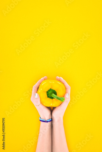 top view of human hands holding fresh raw organic pepper isolated on yellow