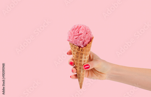 Fototapeta Hand holding strawberry ice cream cone on white background