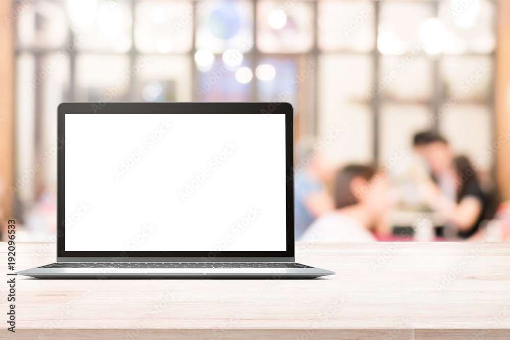 Laptop with blank screen placed on white wooden table in blurred people in coffee shop or restaurant Laptop with blank screen placed on white wooden table in blurred people in coffee shop or restaurant