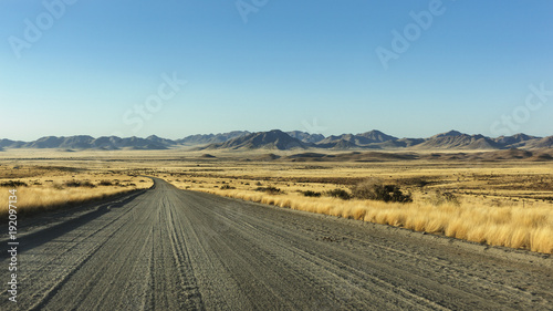 gravel road passing through the steppe mountains in the background