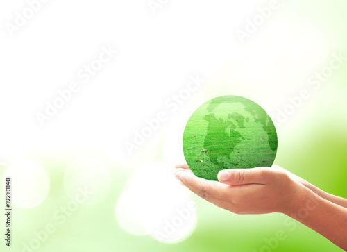 World environment day concept: Businessman hand holding earth globe of grass over blurred green nature background.