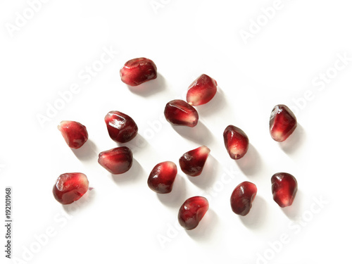 Close up of scattered group of pomegranate seeds isolated on white background - from above