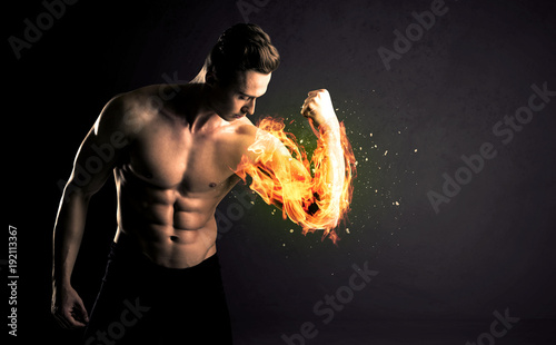 Fotografia Bodybuilder athlete lifting weight with fire explode arm concept