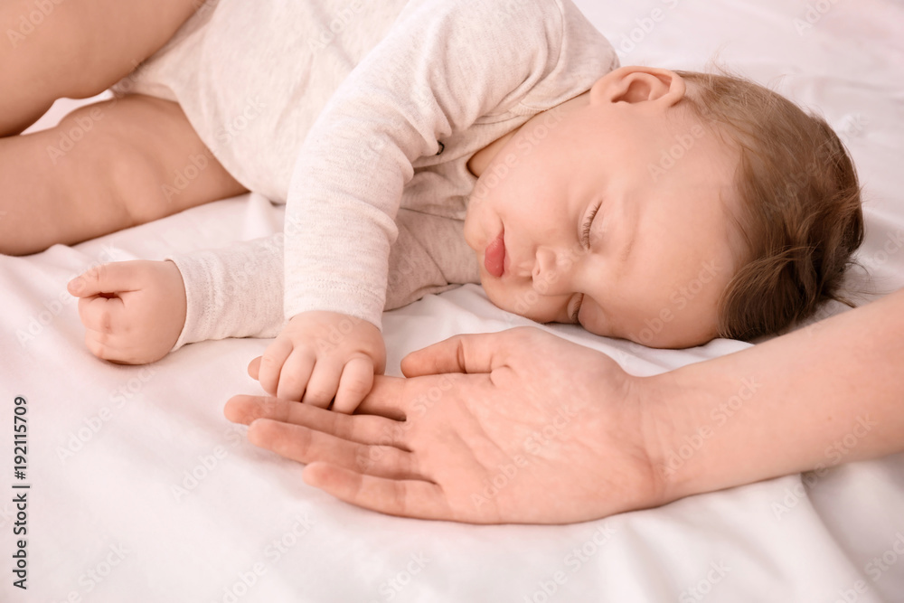 Sleeping baby holding mother's hand on bed Sleeping baby holding mother's hand on bed