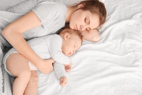 Mother with her baby sleeping on bed at home