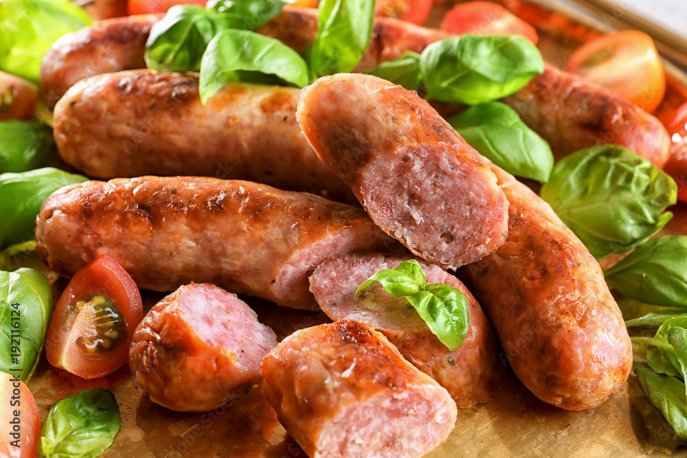 Plate with delicious grilled sausages, tomato and basil, closeup Plate with delicious grilled sausages, tomato and basil, closeup