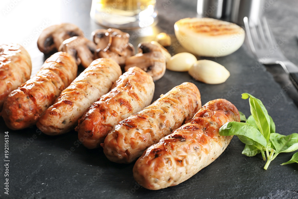 Slate plate with delicious grilled sausages, closeup Slate plate with delicious grilled sausages, closeup