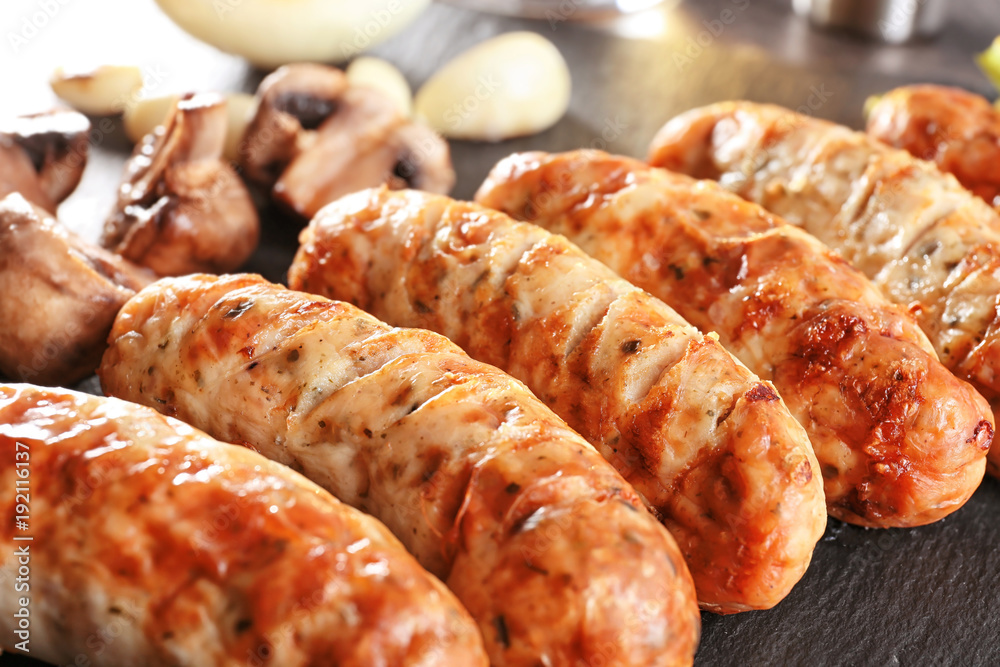Slate plate with delicious grilled sausages, closeup Slate plate with delicious grilled sausages, closeup