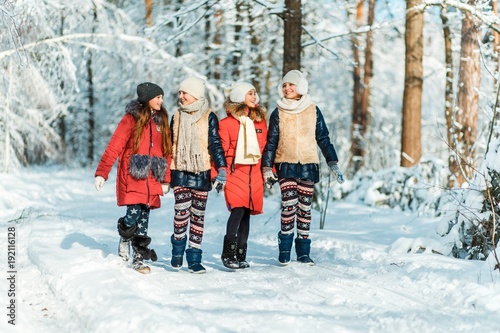 Beautiful teenage girls having fun outside in a wood with snow in winter on a wonderful frosty sunny day. Friendship and active life consept