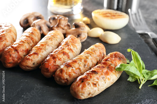 Slate plate with delicious grilled sausages, closeup