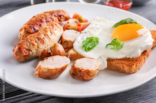 Plate with delicious grilled sausages and fried egg, closeup