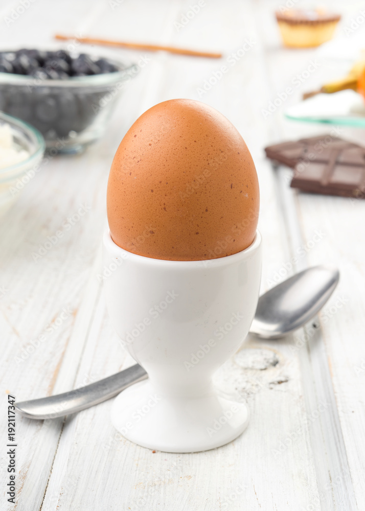 whole egg in cup on white wood with chocolate and berries whole egg in cup on white wood with chocolate and berries