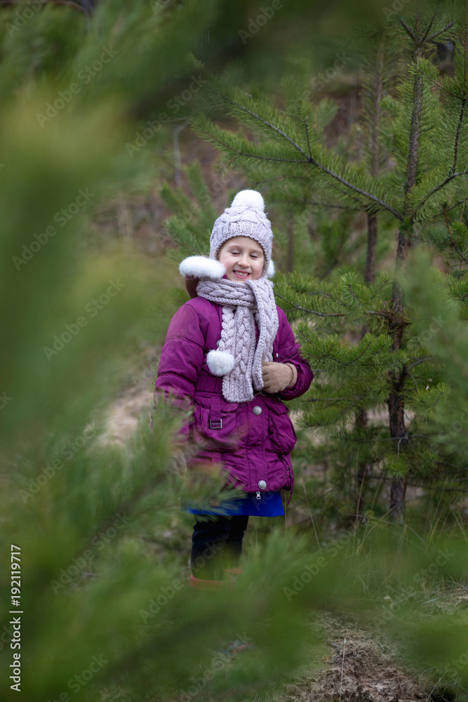A cute little girl in a pine forest in the autumn time. A cute little girl in a pine forest in the autumn time.