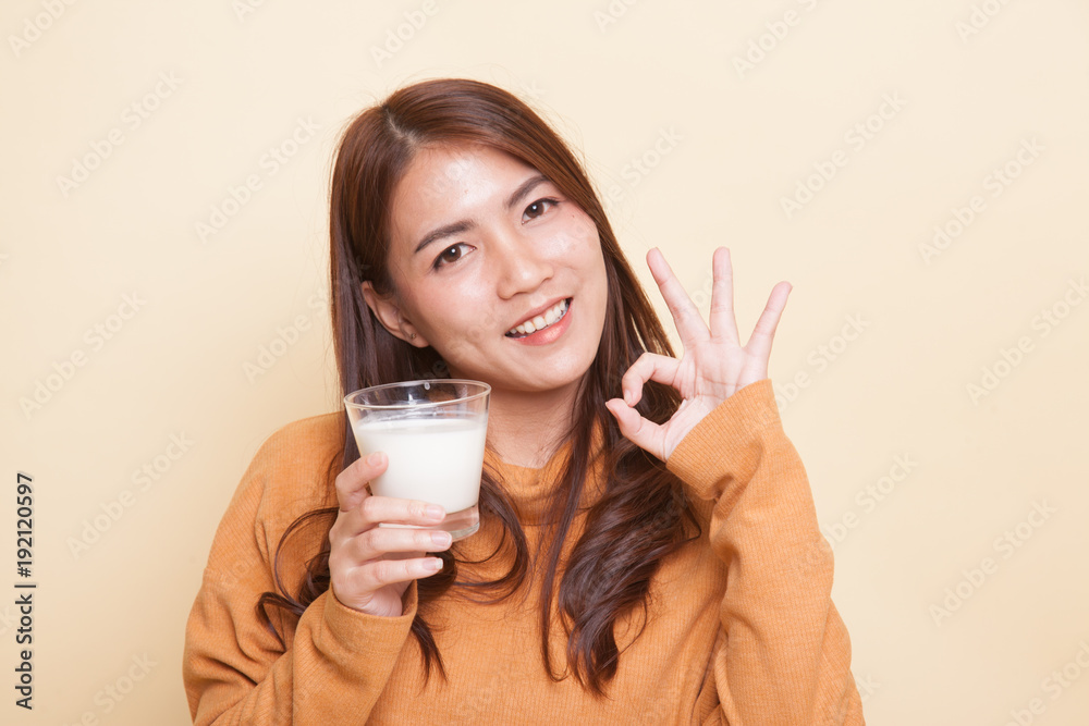 Healthy Asian woman drinking a glass of milk show OK sign. Healthy Asian woman drinking a glass of milk show OK sign.