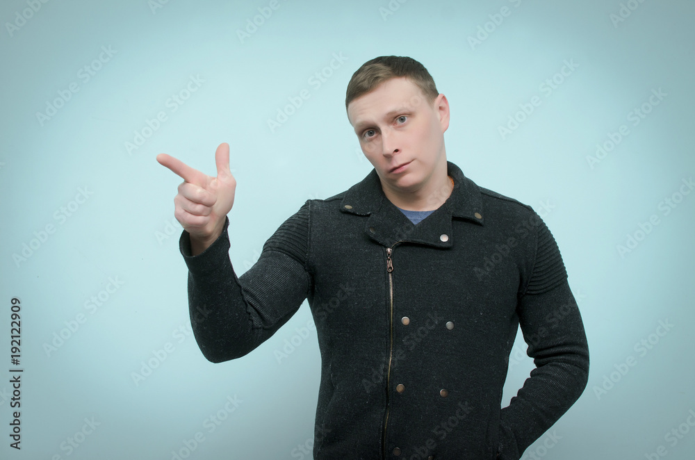 Focused attentive man points a finger at a copy space in front of him or is selecting item from virtual menu isolated on blue background. Focused attentive man points a finger at a copy space in front of him or is selecting item from virtual menu isolated on blue background.