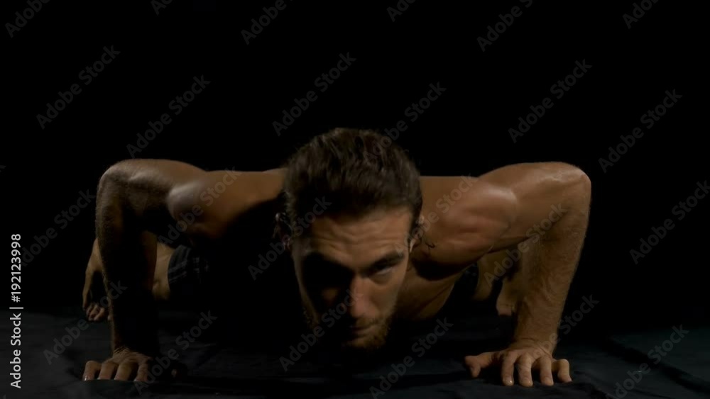 Fitness young man doing push ups on a black background Fitness young man doing push ups on a black background