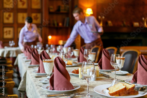 Waiters prepare a table for breakfast. Background. The foreground of napkins, dishes, toast, glasses. Calm atmosphere photo