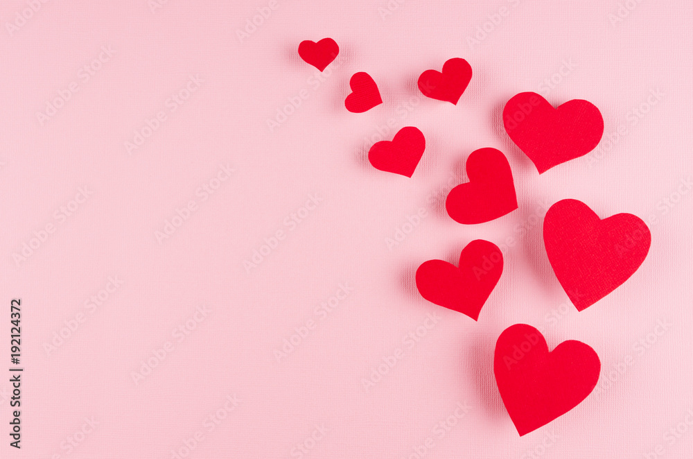 Stream of red paper hearts on soft pink color background, copy space. Valentines day art.