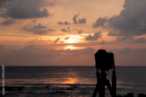 A silhouette of a DSLR Camera shooting the dramatic sunset by the beach.